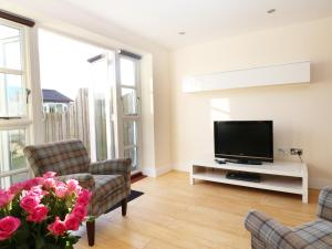 a living room with a flat screen tv and pink flowers at 24 Bay Retreat Villas in St Merryn