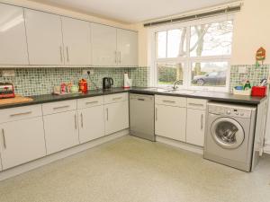 a kitchen with white cabinets and a washing machine at Laurel Bank Cottage in Embsay