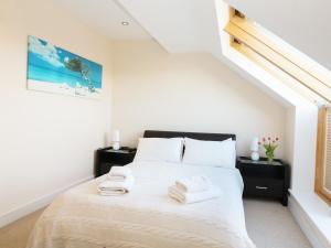 a bedroom with a white bed with towels on it at 24 Bay Retreat Villas in St Merryn