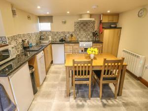 eine große Küche mit einem Holztisch und Stühlen in der Unterkunft Bluebird Cottage in Parwich