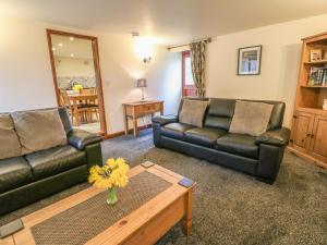a living room with two leather couches and a coffee table at Bluebird Cottage in Parwich