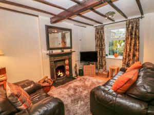 a living room with a leather couch and a fireplace at Elderbank in Bradwell