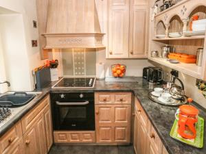 a kitchen with wooden cabinets and a black stove top oven at Elderbank in Bradwell