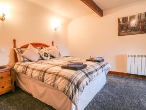 Schlafzimmer mit einem großen Bett mit einem Kopfteil aus Holz in der Unterkunft Bluebird Cottage in Parwich