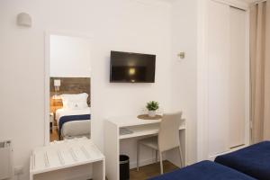 ein Zimmer mit einem Bett und einem Schreibtisch mit einem Fernseher an der Wand in der Unterkunft Hotel Veleiro in Sines