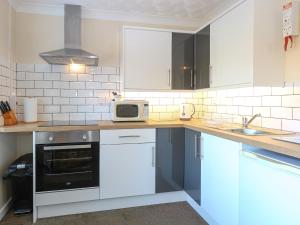 a kitchen with white cabinets and a microwave at Robyn's Nest in Sharrington