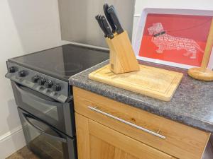 una cucina con blocco di coltello su un bancone accanto a un piano cottura di 1 Primitive Mews a Chelmorton