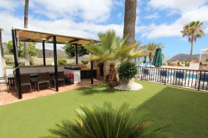 a patio with a lawn with a table and a grill at ViVa Royal - Immense villa, unique and exclusive in Chayofa
