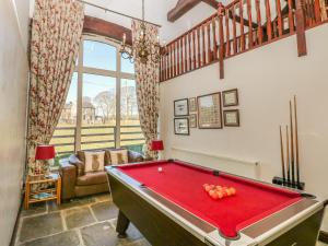 a pool table in a living room with a red pool table at Bullace Barn in Thurlstone
