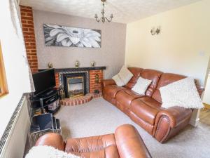 a living room with a leather couch and a fireplace at Bramble Grange in Overseal