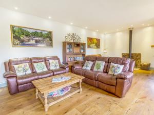 uma sala de estar com sofás de couro castanho e uma mesa de centro em Cobblers Barn em Mickleton