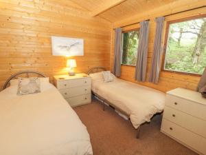 two beds in a log cabin with a window at Y Caban in Llangelynin