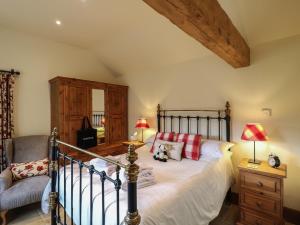 a bedroom with a large bed and a chair at The Cow Shed in Stanton in Peak