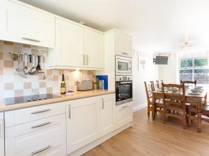 a kitchen with white cabinets and a dining table at 1 Springwater View in Mickleton