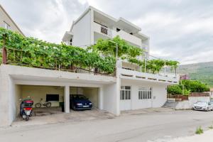 una casa blanca con un garaje con una motocicleta estacionada en ella en Apartments Flor de Lis en Podstrana