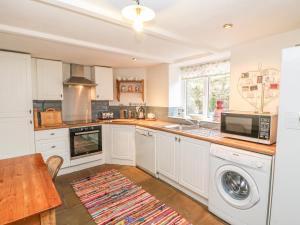 a kitchen with white cabinets and a sink and a microwave at Hoodgill Barn in Newbiggin