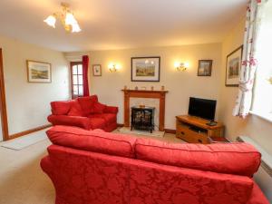 a living room with a red couch and a fireplace at Barnbrook in Carperby