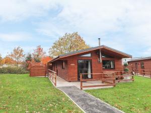 a log cabin with a porch and green grass at The Roe in St Asaph