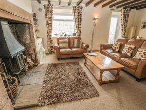 sala de estar con muebles de cuero y chimenea en Shepherds Nook en North Charlton