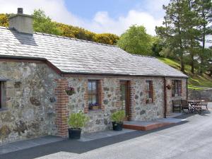 een stenen huis met een tafel en een patio bij Penrallt Cottage in Y Felinheli