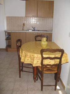 eine Küche mit einem Tisch mit Stühlen und einer gelben Vase darauf in der Unterkunft Maison de caractère, pierre sèche, Galéria, pour 2 in Galeria