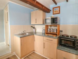 cocina con armarios de madera, fregadero y microondas en Frodos, en Henstridge