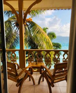 balcón con 2 sillas y vistas al océano en Patatran Village Hotel, en La Digue