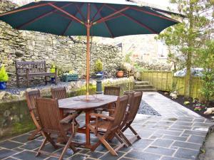 a wooden table with chairs and an umbrella on a patio at Briarcliffe Cottage in Lindale