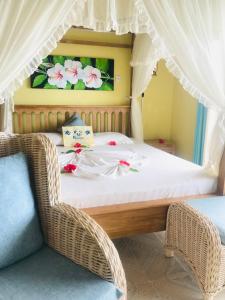 een slaapkamer met een bed en een rieten stoel bij Patatran Village Hotel in La Digue