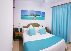 a bedroom with a large bed with blue curtains at Apartamentos Costa Menorca in Cala en Bosc