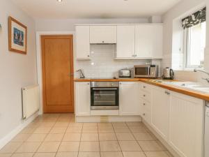a kitchen with white cabinets and a sink at 5 Cae Derwydd in Cemaes Bay
