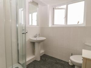 a white bathroom with a sink and a toilet at 5 Cae Derwydd in Cemaes Bay +21 photos