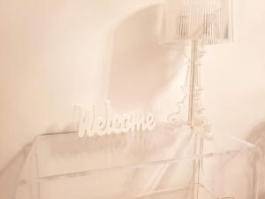 a white table with a lamp and a white sign at Lemesou Apartments in Patra