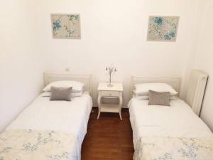 Cette chambre comprend deux lits et une table avec une table de chevet. dans l'établissement Lemesou Apartments, à Patras