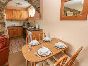 cocina y comedor con mesa de madera y sillas en Eynons Cottage, en Roch
