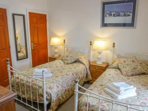 a bedroom with two beds and two lamps and a mirror at 2 Primitive Mews in Chelmorton