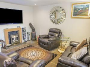 2 Primitive Mews في Chelmorton: غرفة معيشة مع أثاث من الجلد وتلفزيون بشاشة مسطحة