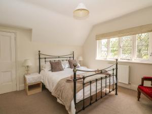 a bedroom with a bed and two windows at Gun End Cottage in Rushton Spencer