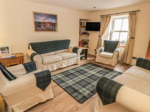 a living room with couches and chairs and a tv at Alma Cottage in Tyndrum