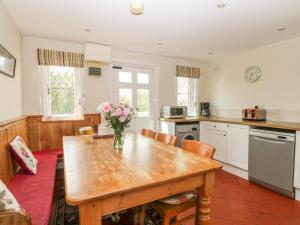 a kitchen with a wooden table with a vase of flowers on it at Gun End Cottage in Rushton Spencer
