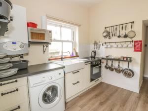 eine Küche mit einer Waschmaschine und einem Waschbecken in der Unterkunft Alma Cottage in Tyndrum