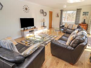 a living room with leather furniture and a flat screen tv at Llecha in Llysfaen
