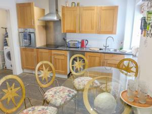 uma cozinha com uma mesa de vidro e armários de madeira em 2 Primitive Mews em Chelmorton