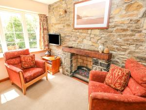 a living room with two chairs and a stone fireplace at Eynons Cottage in Roch