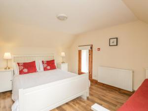 um quarto com uma cama branca e almofadas vermelhas em 10 Monarch Country Apartments em Newtonmore