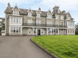 a large stone house with a large yard at 10 Monarch Country Apartments in Newtonmore