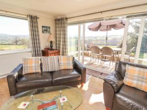 a living room with two leather couches and a table at Llecha in Llysfaen