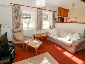 een woonkamer met een bank en stoelen en een tv bij Lane Fold Cottage in Grassington