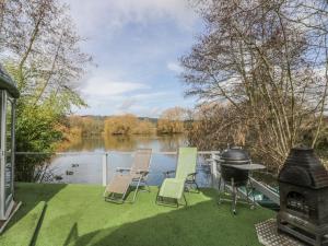 a patio with chairs and a grill next to a lake at Lakeview Yurt in Beckford