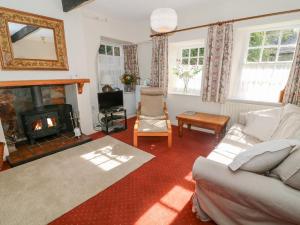 een woonkamer met een bank en een open haard bij Lane Fold Cottage in Grassington